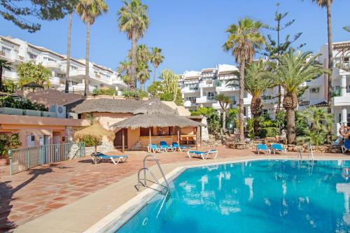 福恩吉罗拉Apartamento en complejo con piscina, pádel y restaurante con vistas al golf en Mijas - Matchroom 83的棕榈树和建筑度假村内的游泳池