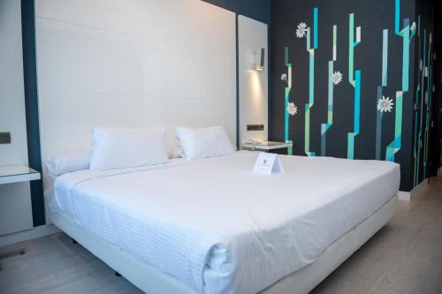 马拉加Hotel Málaga Nostrum Airport的卧室配有白色的床,上面有标志