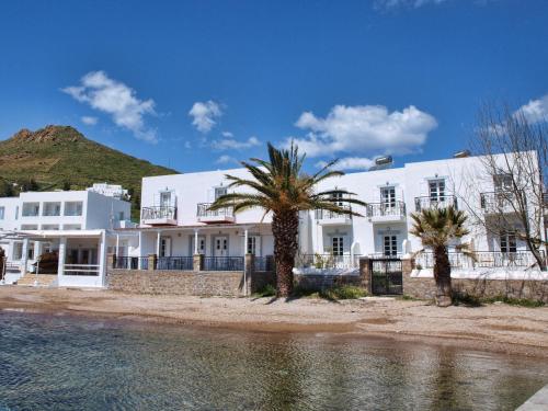 Grikos银滩酒店的一座棕榈树成荫的白色建筑,毗邻一片水体