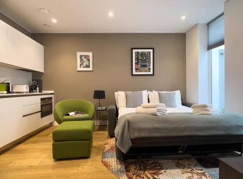 伦敦Mirabilis Apartments - Bayham Street的一间卧室配有一张床和一把绿色椅子