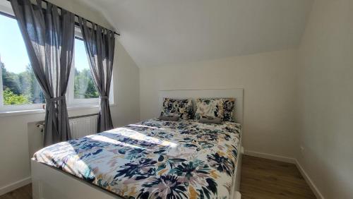 拉脱维亚Villa Saulkrasti Balta Kapa White Dunes的一间卧室配有一张带花卉棉被的床和窗户。