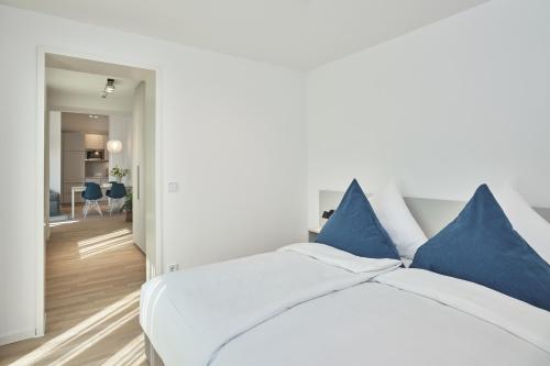 朗格奥Lüttjeod Apartmentvilla Lüttjeod Apartmentvilla 06的一间卧室配有白色床和蓝色枕头