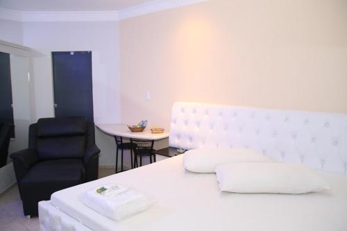 费尔南多波利斯SAFIRA MOTEL II的卧室配有白色的床和黑椅