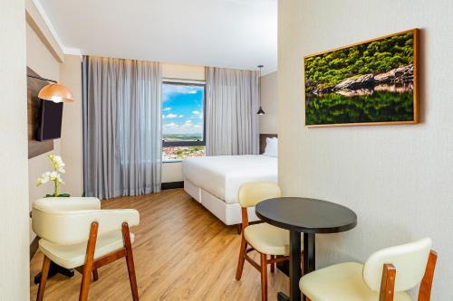 费拉迪圣安娜NH HOTEL FEIRA DE SANTANA的酒店客房带一张床、一张桌子和椅子