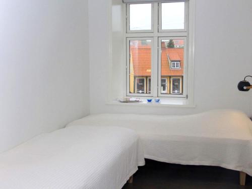 斯瓦讷克Holiday home Svaneke XLI的白色客房的两张床,设有窗户