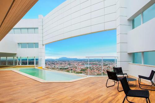 费拉迪圣安娜NH HOTEL FEIRA DE SANTANA的从带椅子和游泳池的建筑屋顶上可欣赏到风景