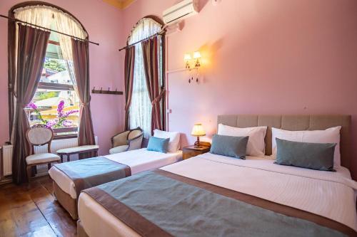 比于卡达Büyükada Anastasia Meziki History Mansion的配有粉红色墙壁和窗户的客房内的两张床