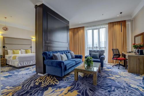 比什凯克Garden Hotel & SPA的酒店客房配有蓝色的沙发和床。