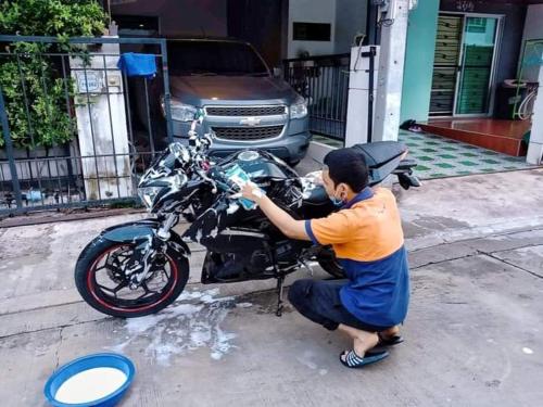 尖竹汶บ้านสวนเนินเห็ด的一个人在街上洗摩托车