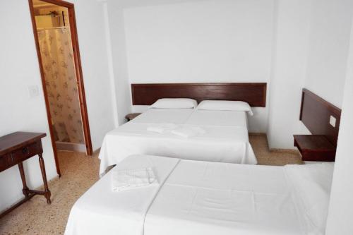 贝尼卡西姆Hostal La Torre的酒店客房,设有三张床和镜子