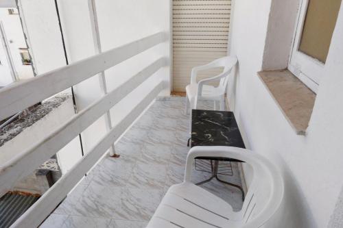 贝尼卡西姆Hostal La Torre的阳台配有2把白色椅子和长凳