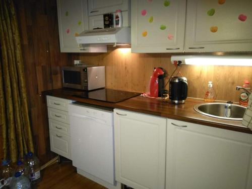 萨翁林纳Holiday Cabin Kerimaa 41的厨房配有白色橱柜、水槽和微波炉