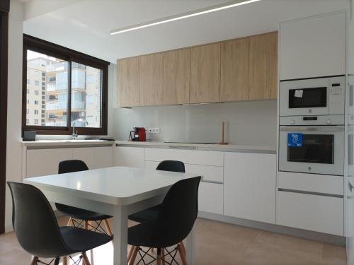 贝尼卡西姆Residencial El Trenet 2C的厨房配有白色橱柜和桌椅