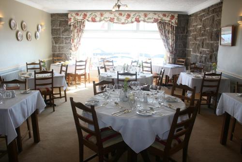 朗德斯通Roundstone House Hotel的一间设有白色桌椅和窗户的用餐室