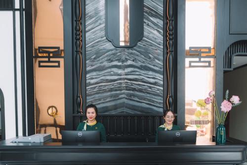 大叻Goldient Boutique Hotel的两名妇女坐在一张桌子上,手提电脑