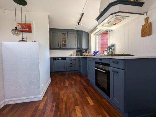 特罗姆瑟Sea & Mountain View Apartment Tromsø的厨房铺有木地板,配有蓝色橱柜。
