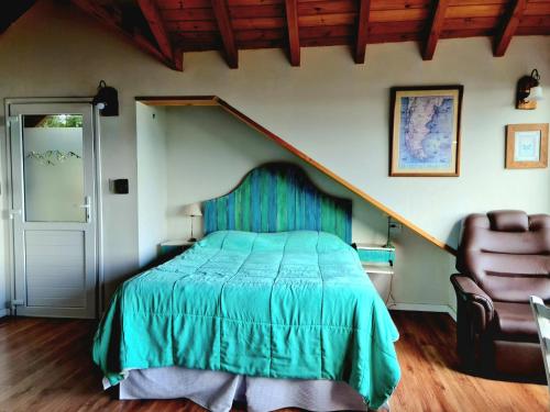 拉安戈斯图拉镇Puerto Esmeralda ESPECTACULAR DEPTO CON VISTA AL LAGO NAHUEL HUAPI的一间卧室配有绿色的床和椅子