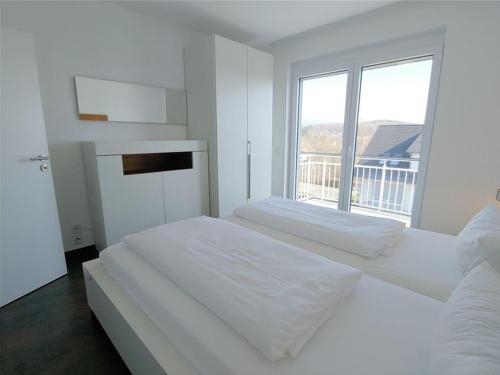 巴特贝林根Golf & Wellness Suite Bad Bellingen Apartment 5-9的白色的卧室设有一张大床和一个窗户