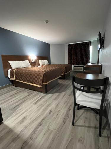 钱诺夫Relax Inn Channelview的一间卧室配有一张床、一张桌子和一张桌子