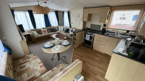 拉尔Cozy Private Static Caravan at Llyons Robin Hood - Silver Birch Way 11的一间厨房和客厅,客厅内配有一张小桌子