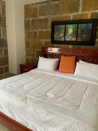 OibaHotel Hacienda Guane Urbano的一张大白色的床,上面有两个橙色枕头