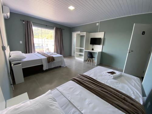 佩尼亚Pousada da Bia Praia的一间卧室设有两张床和大窗户