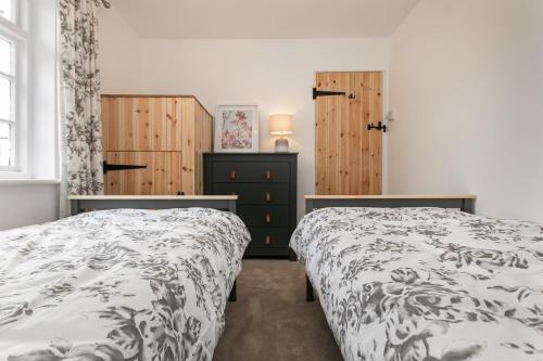 Saint OsythMill Dam Lake House的一间卧室设有两张床和木制橱柜。
