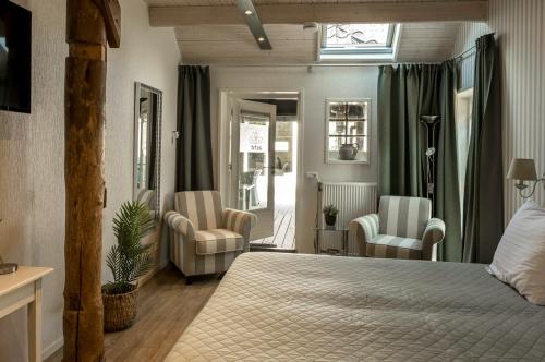 泽伊德拉伦Hotel B&B Hoeve de Vredenhof的一间卧室配有一张床、两把椅子和一个窗户