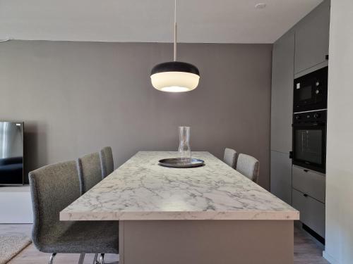 奥斯陆Modern and Central Apartment, 6 mins to Oslo City的厨房配有大理石桌子、椅子和安达灯