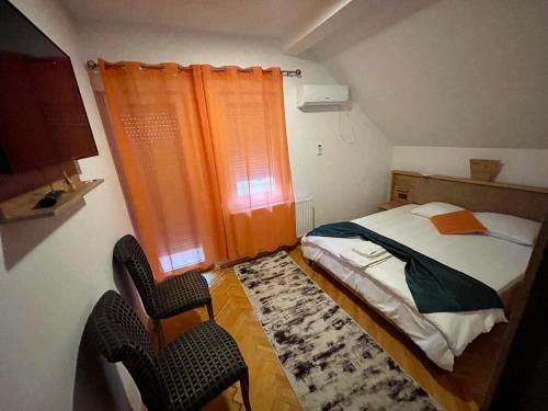 Kosovo PoljeMadigan's Hotel的一间小卧室,配有一张床和两把椅子