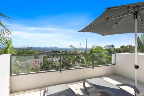 努萨角诺萨蓝色度假酒店的阳台配有椅子和遮阳伞。