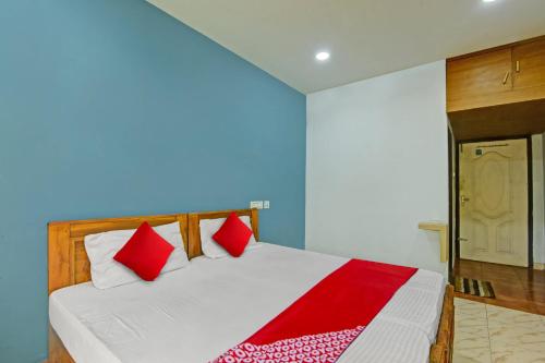 KondottiOYO Flagship Karipur Residency的卧室配有带红色枕头的白色床