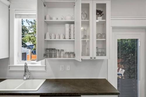 乔治王子城Comfort and joy的厨房配有白色橱柜、水槽和窗户。