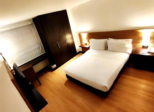 波哥大68号斯卡拉酒店的卧室配有一张白色大床和一张书桌