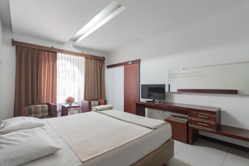 万隆Istana Hotel Bandung Mitra RedDoorz的一间卧室配有一张床、一张书桌和一台电视