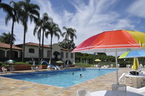 塞拉内格拉Hotel Fazenda São Matheus的一个带遮阳伞的游泳池,水中有人