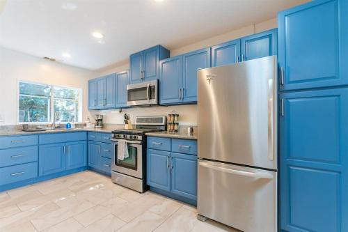 奥克兰Home and Cottage in Mosswood的厨房配有蓝色橱柜和不锈钢冰箱