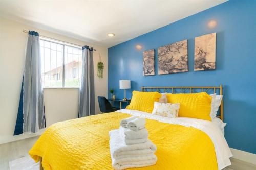 奥克兰Home and Cottage in Mosswood的蓝色卧室配有黄色的床和毛巾