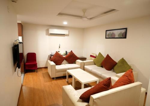 卡努尔Hotel Sasya Pride的客厅配有白色沙发和红色椅子