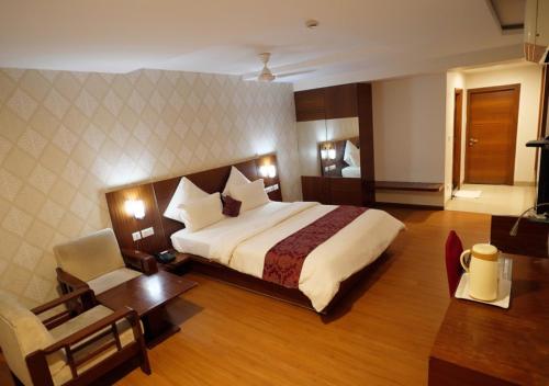 卡努尔Hotel Sasya Pride的酒店客房设有一张大床和一张书桌。