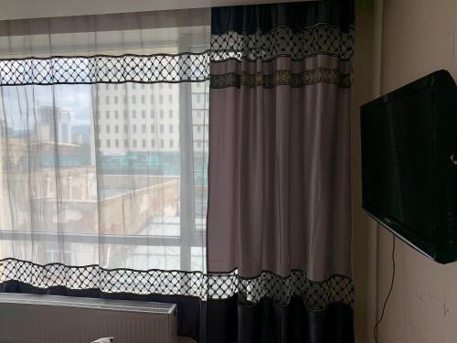 乌兰巴托2 bedrooms apartment的客房设有带窗帘的窗户和电视。