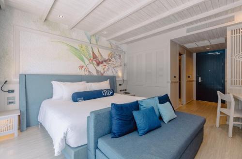 普吉镇Hotel Tide Phuket Beach Front的一间卧室配有一张大床和一张蓝色的沙发