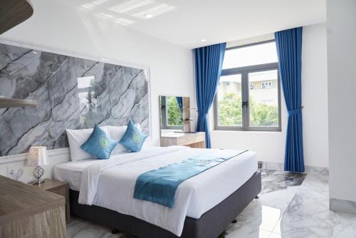 Long ThànhKhang Thịnh Hotel Long Thành的一间卧室配有一张带蓝色窗帘的大床