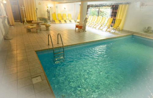 富尔普梅斯Hotel Garni Hubertus-Nostalgie & Charme的一个带黄色椅子的房间的大型游泳池