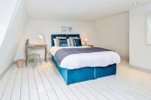 LincolnshireVictorian townhouse - Stamford centre - 2 big bedrooms, living room kitchen etc tastefully decorated的一间卧室配有一张蓝色的床、一张桌子和一把椅子