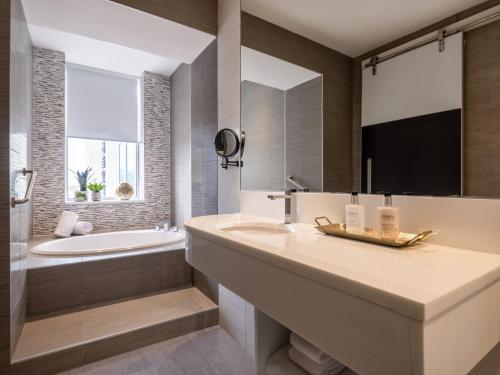 法拉盛voco Fiorello - LaGuardia East, an IHG Hotel的浴室配有水槽、浴缸和浴缸。