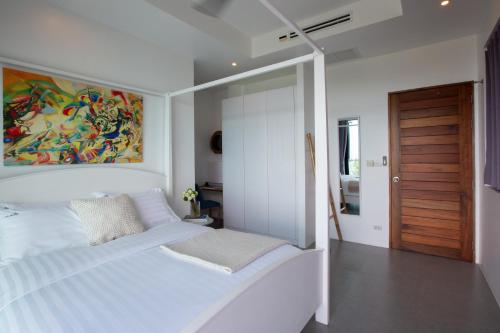 苏梅岛Villa La Moon Chaweng Noi 4BR的卧室配有一张白色床,墙上挂有绘画作品