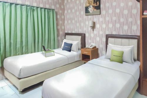Klandasan KecilHotel Syariah Citra Nusantara Balikpapan的配有绿窗帘的酒店客房的两张床