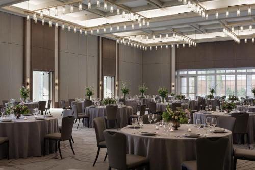 夏洛茨维尔Kimpton - The Forum Hotel, an IHG Hotel的宴会厅配有桌椅和吊灯