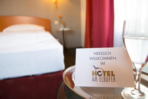 汉堡Hotel AM ELBUFER的一张桌子,上面有酒杯和招牌
